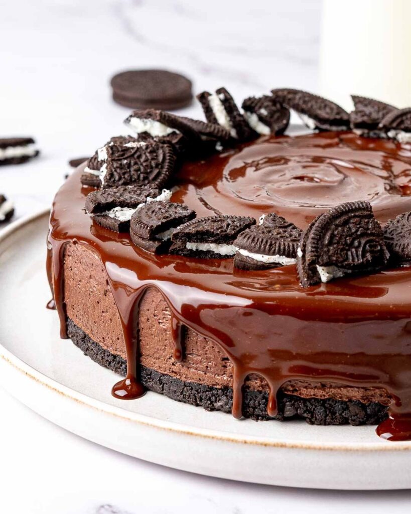 Chocolate cheesecake with chocolate ganache dripping down the side with Oreo cookies on top.